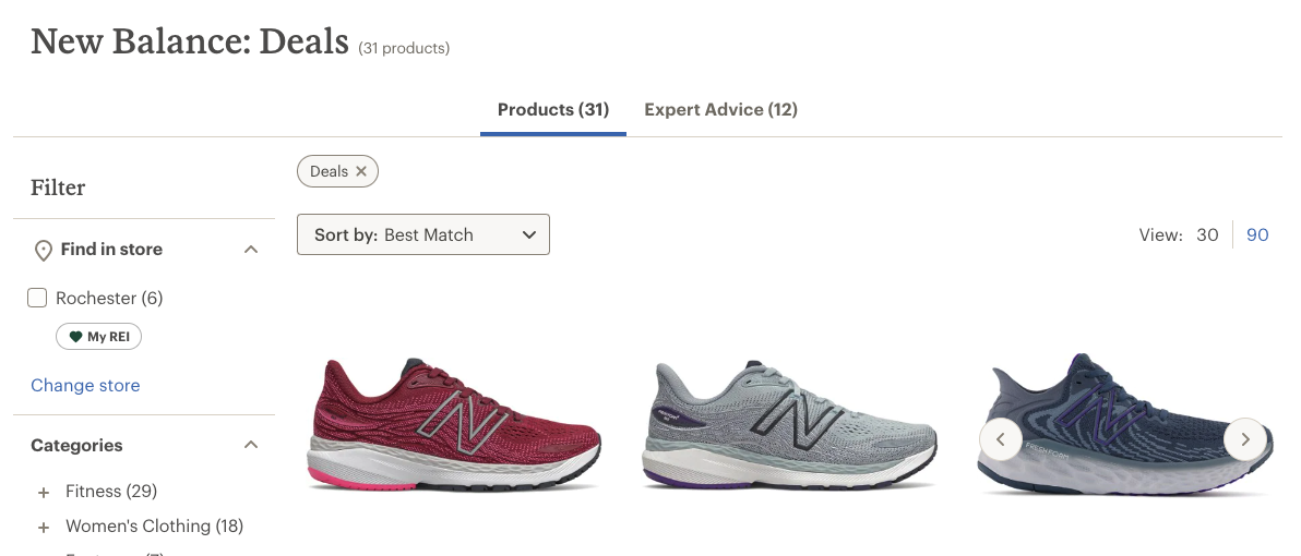 A screenshot of REI.com shows their current discounts on New Balance sneakers. There is an image of three New Balance sneakers, side-by-side—a red sneaker, a gray sneaker, and a mult-colored black and gray sneaker.